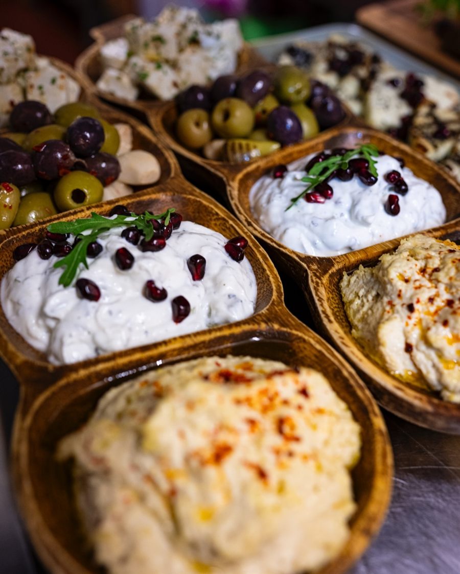 A spread of mezze dishes and dips laid out across a table with warm flatbread.