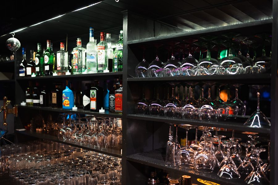 The back bar: lit shelves of spirits, rows of upturned glassware and a small mirrorball.